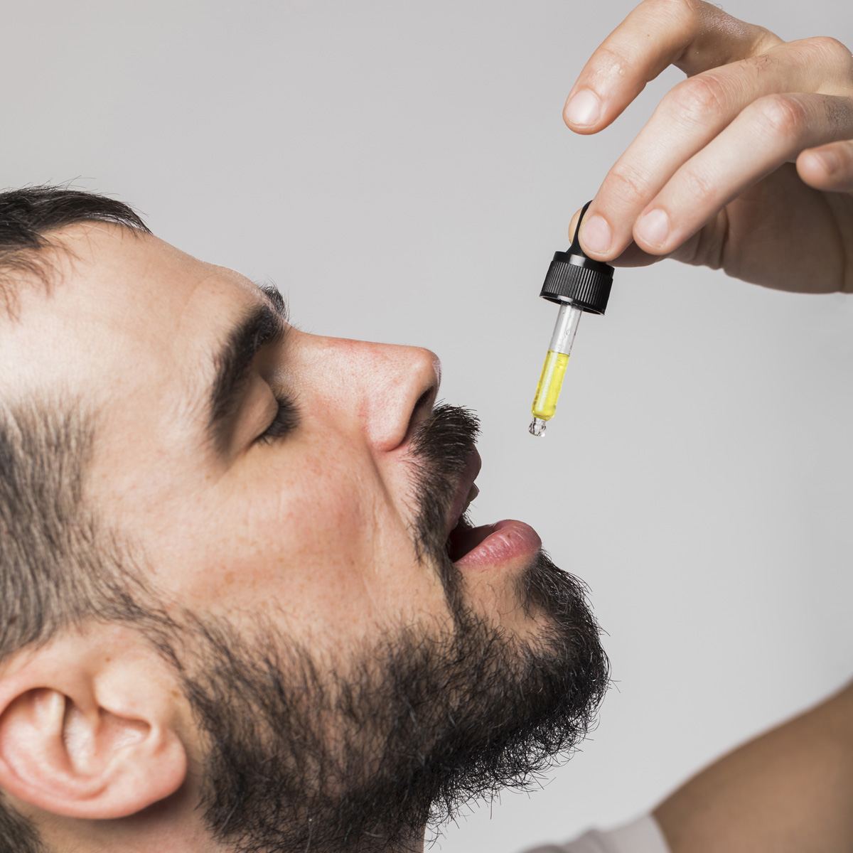 Homme prenant des gouttes d’huile CBD par voie sublinguale