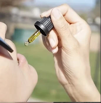 Personne utilisant une pipette d’huile sous la langue